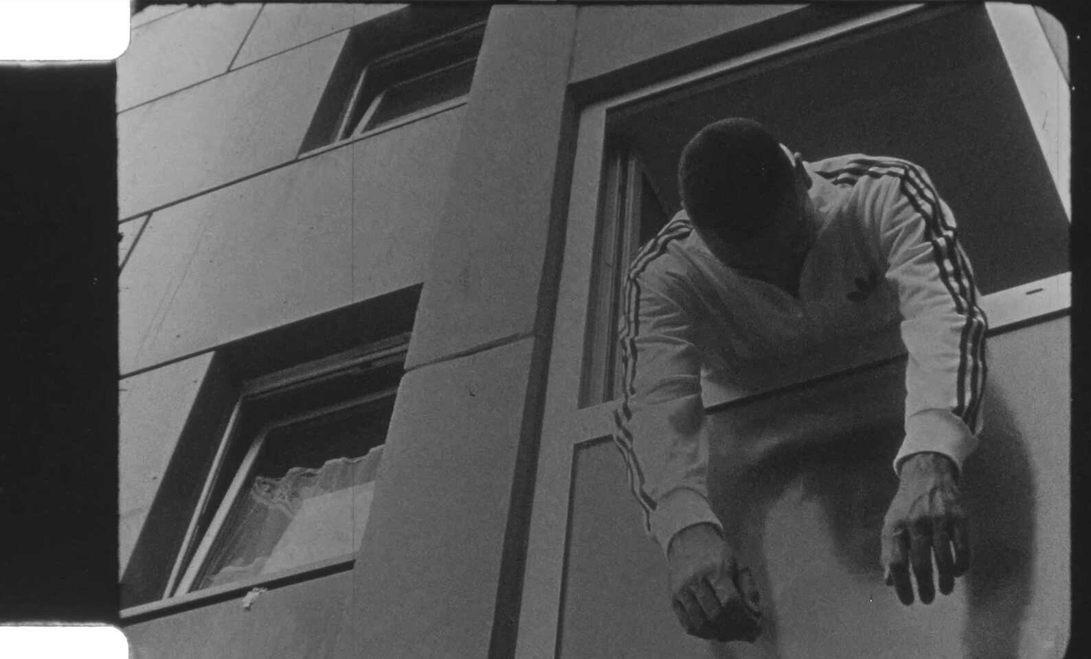 Young man leaning forward in front of an apartment building