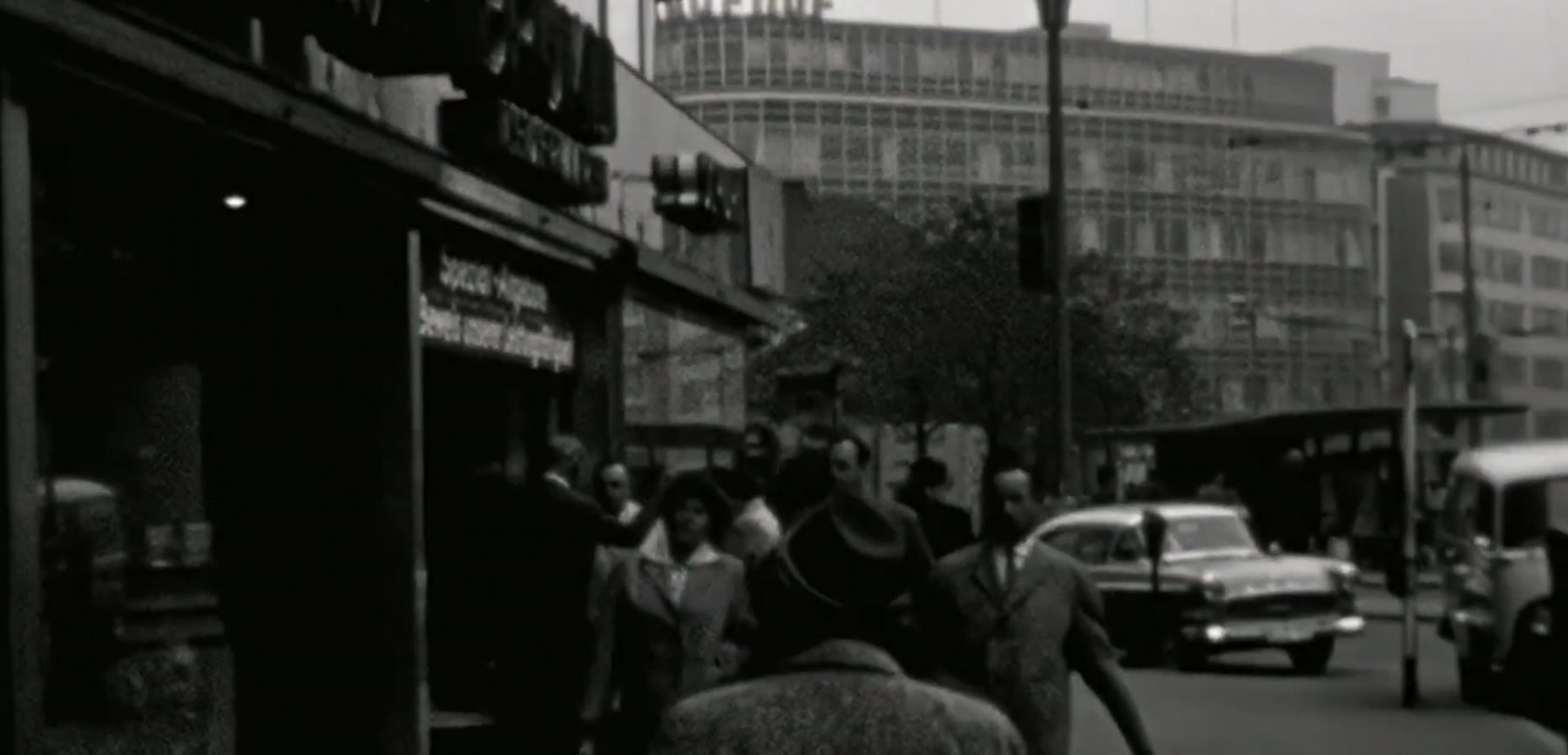 Black-and-white archival street scene in Frankfurt with pedestrians and period cars